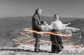 A couple dancing in a field with digital swooshes surrounding them.